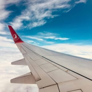 Photo of an airplane wing against a vivid blue sky and soft clouds.