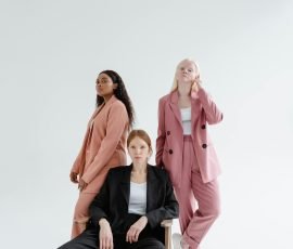 Three diverse businesswomen in stylish suits on a studio white background, exuding confidence.